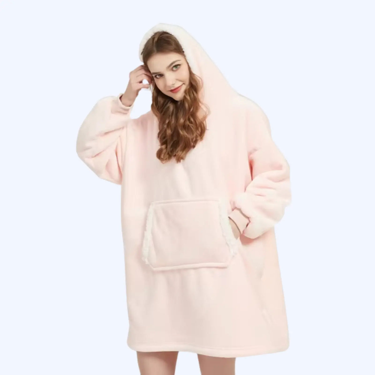 Woman wearing a light pink hoodie blanket with sherpa-lined hood and pocket. 